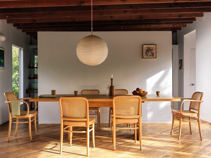 Dining room with large table, six chairs, and paper pendant light above